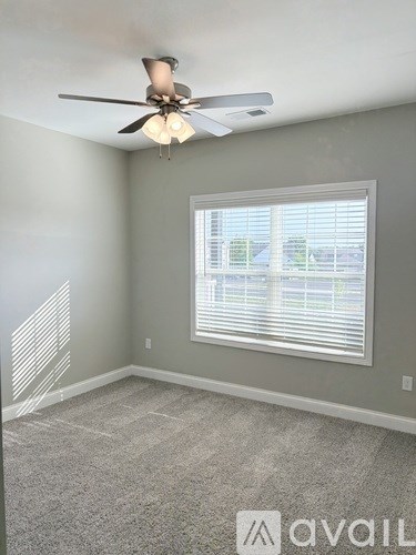 A room with a ceiling fan and a window with blinds.