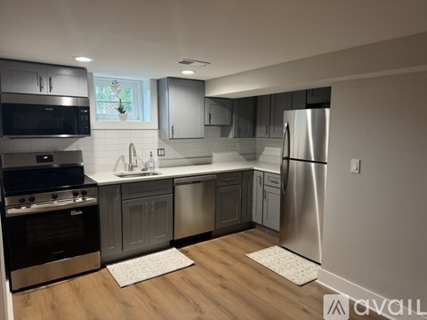 A modern kitchen with stainless steel appliances and wooden flooring.