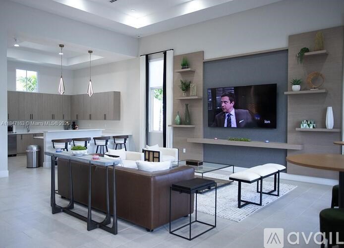 A modern living room with a television and a kitchen area in the background.