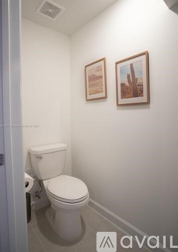 A white toilet in a small bathroom with two pictures on the wall.
