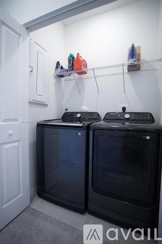 Two black ovens are in a white room.