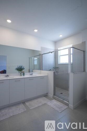 A bathroom with a glass shower stall and a white counter.