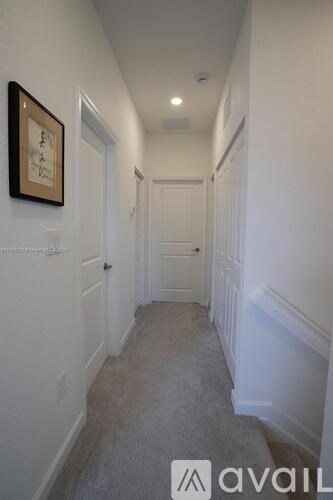 A hallway with a carpeted floor and white walls.