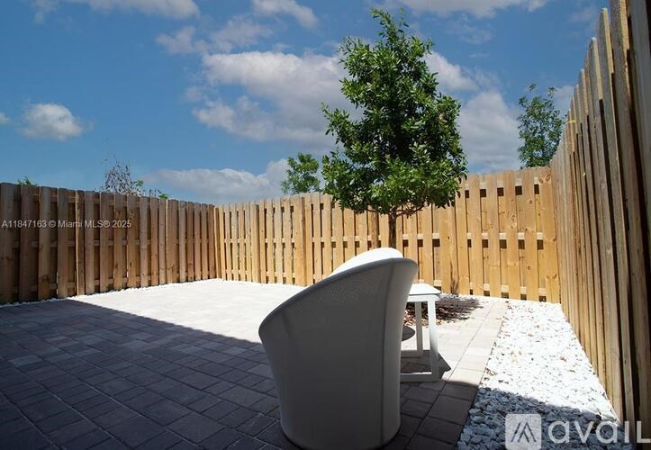 A patio with a white chair and table with a wooden fence in the background.