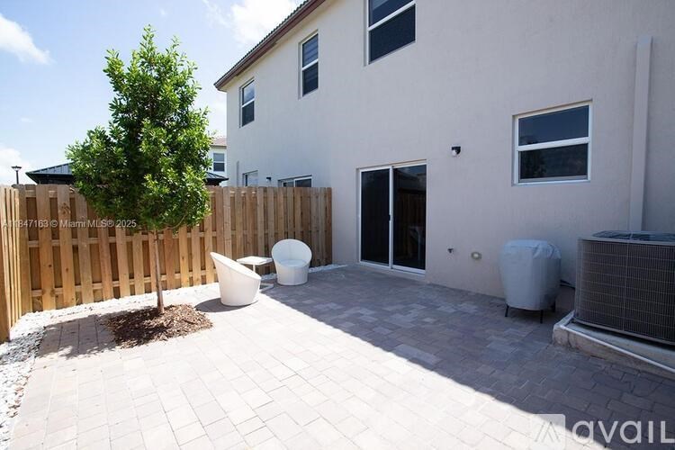 A white house with a wooden fence and a tree in the front yard.