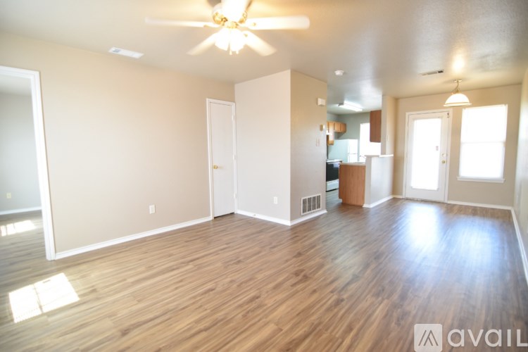 A spacious room with wooden floors and a ceiling fan.
