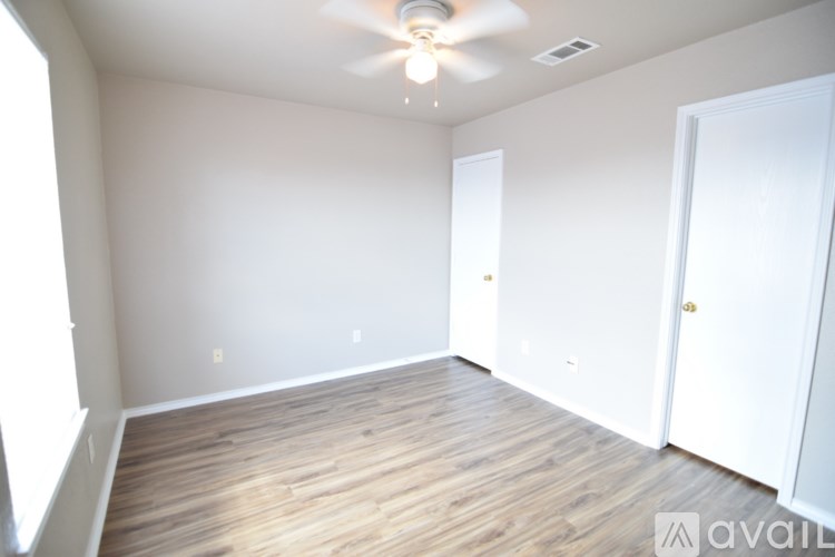 A room with a ceiling fan and wooden flooring.
