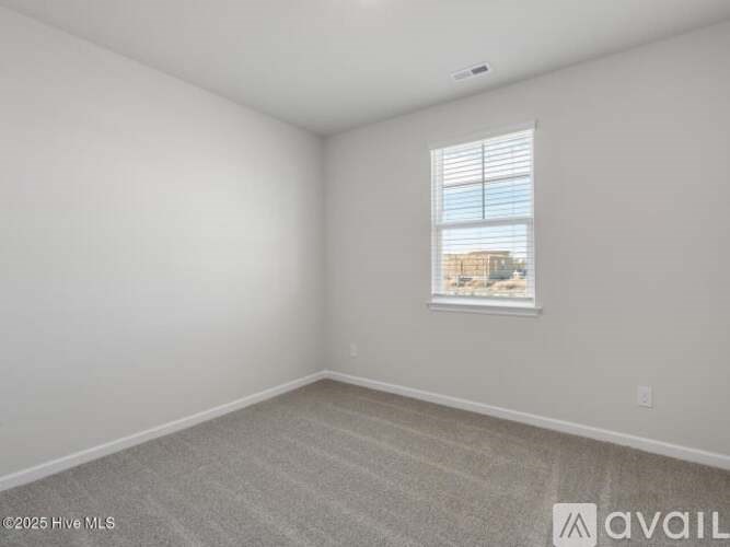 A room with a window and a carpeted floor.