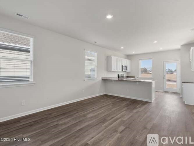 A spacious room with wood flooring and white walls.