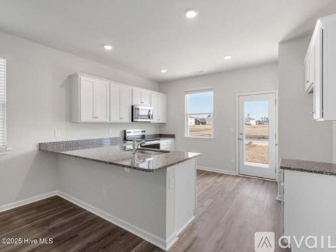 A kitchen with white cabinets and a granite countertop.