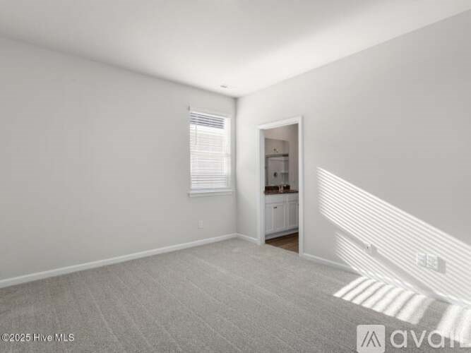 A white room with a window and a door leading to another room.