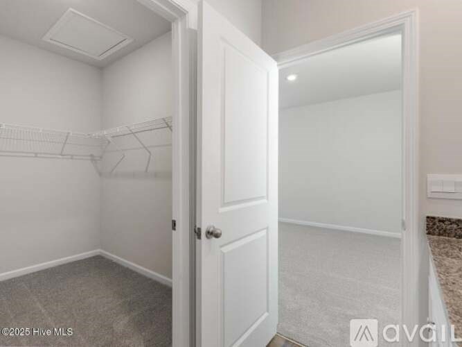 A white door is open to a room with a white wall and a white floor.