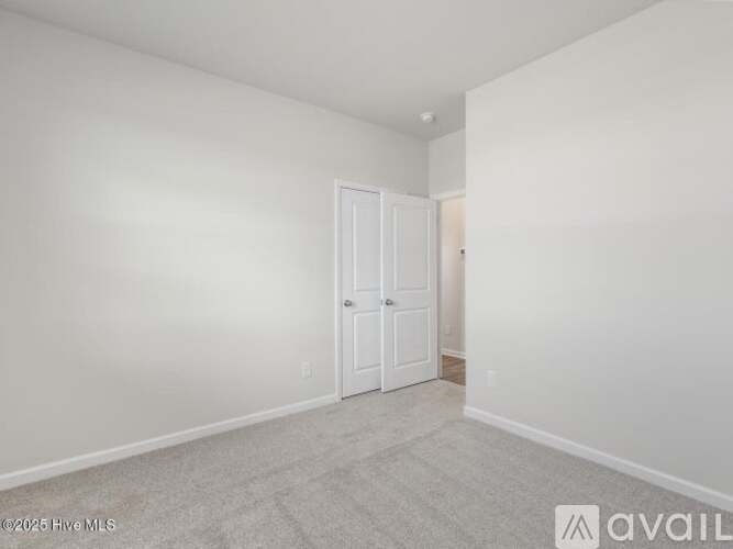 A white room with a carpeted floor and a white door.