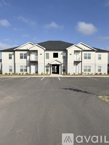 A large white building with a black roof and a parking lot in front.