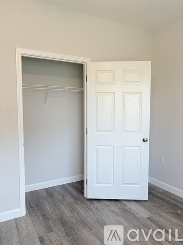 A white door is open to a room with a grey floor.