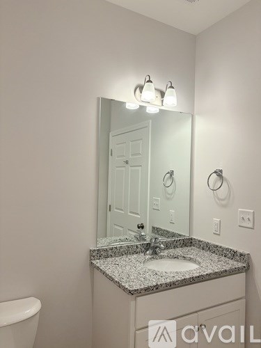 A bathroom with a granite countertop and a white toilet.
