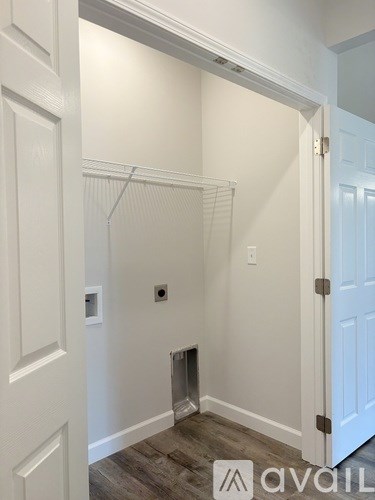A white door is open to a hallway with a light switch and a vent on the wall.