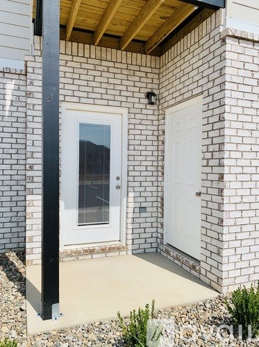 A white door is on the right of a white brick house.