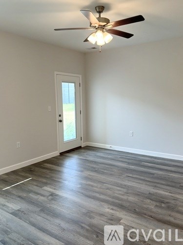 A room with a ceiling fan and a door leading outside.