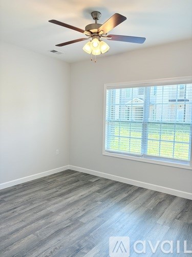 A room with a ceiling fan and a window overlooking a cityscape.