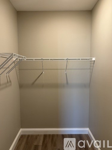 A small, empty closet with a wooden floor and white walls.