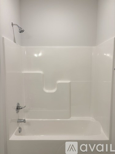 A white bathtub with a shower head attached to the wall.