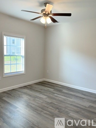 A room with a ceiling fan and a window with blinds.