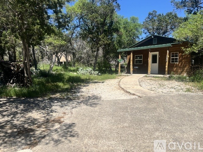 A small building with a green roof is surrounded by trees and grass.