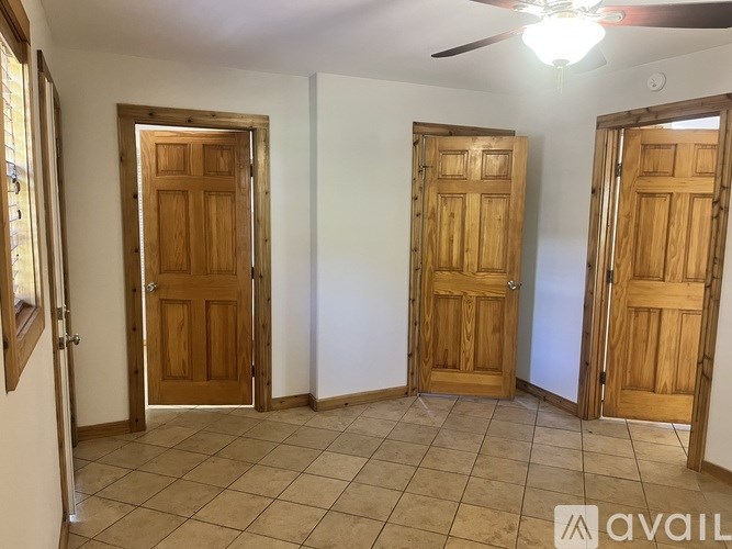 Three wooden doors in a room with tiled flooring and a ceiling fan.