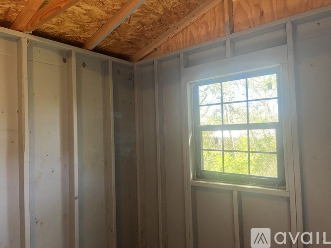 A room under construction with a window showing greenery outside.