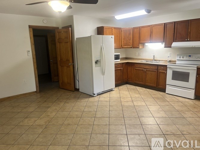 A kitchen with a white refrigerator and brown cabinets.