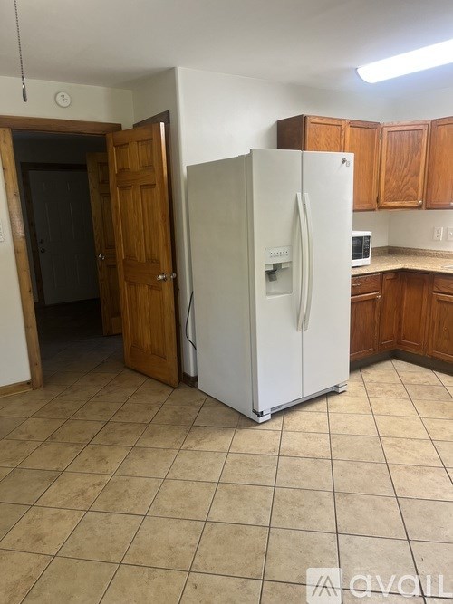 A white refrigerator in a kitchen with wooden cabinets.