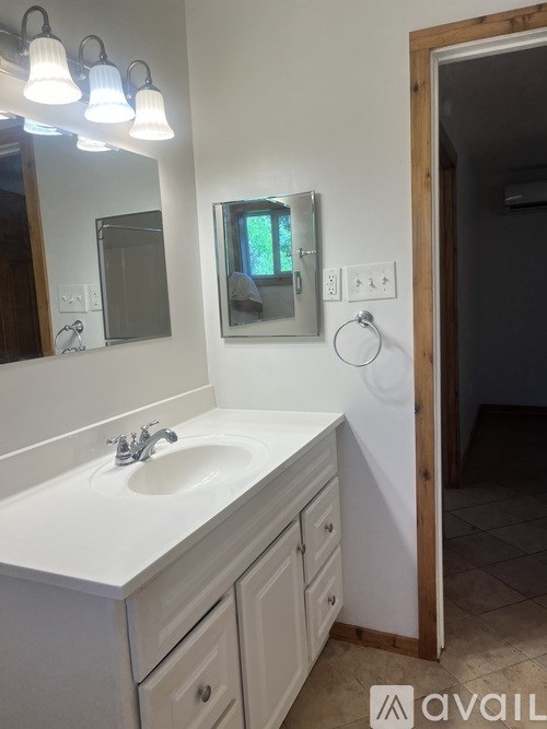 A bathroom with a sink, mirror, and lighting fixture.