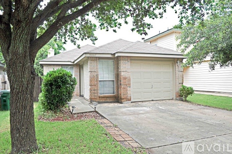 A house with a garage and a tree in front.