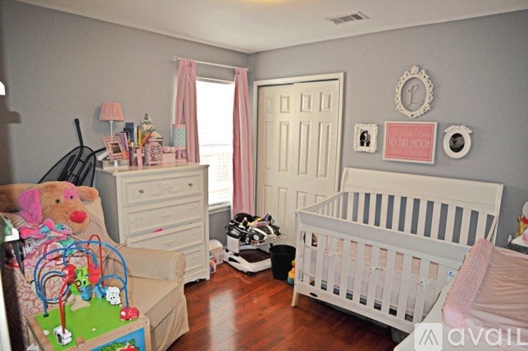 A baby room with a white crib and a teddy bear on the floor.