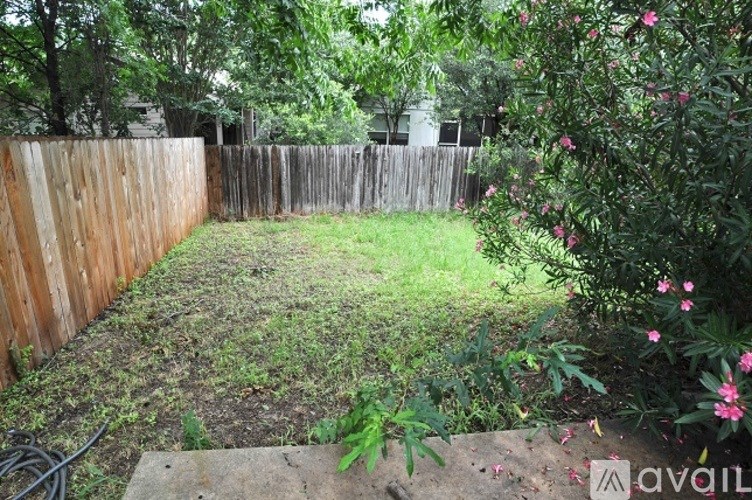 A backyard with a wooden fence and green grass.