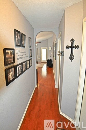 A hallway with a cross on the wall and pictures on the wall.