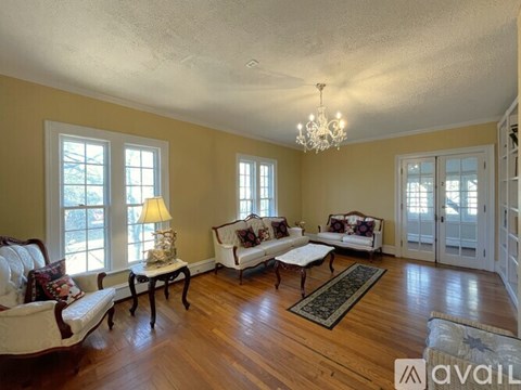 A living room with a couch, chair, and a table with a lamp on it.
