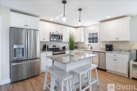 A modern kitchen with white cabinets and stainless steel appliances.