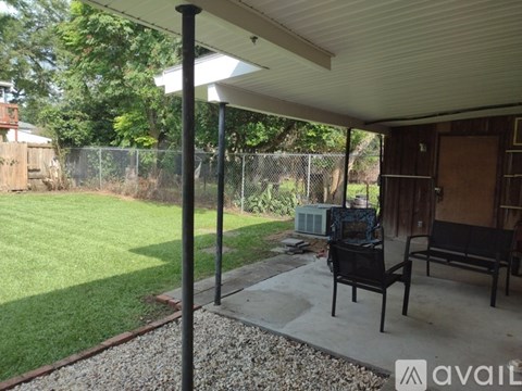 A patio with a black chair and a table with a television on it.