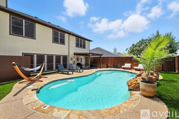 A swimming pool in a backyard with a hammock and patio furniture.