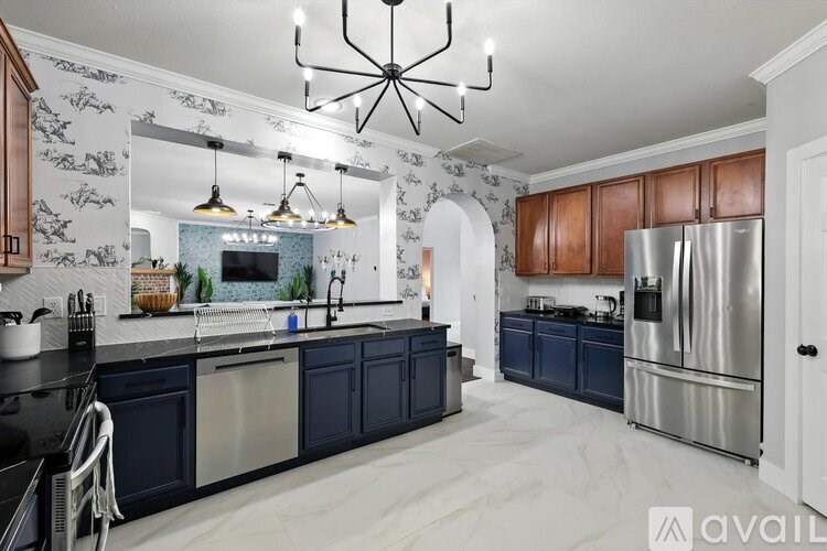 A modern kitchen with dark blue cabinets and a stainless steel refrigerator.