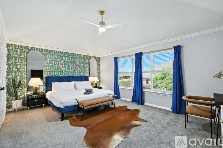 A bedroom with a bed, a chair, and a cowhide rug.