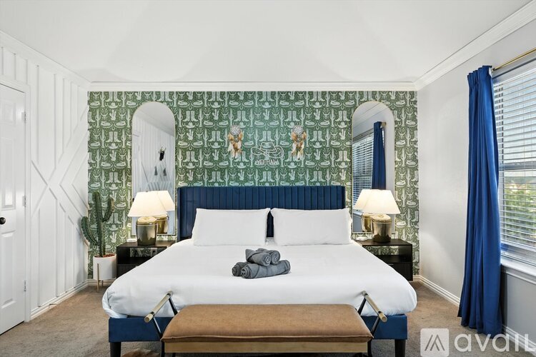A bedroom with a large bed and a green patterned wallpaper.