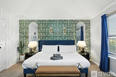 A bedroom with a large bed and a green patterned wallpaper.