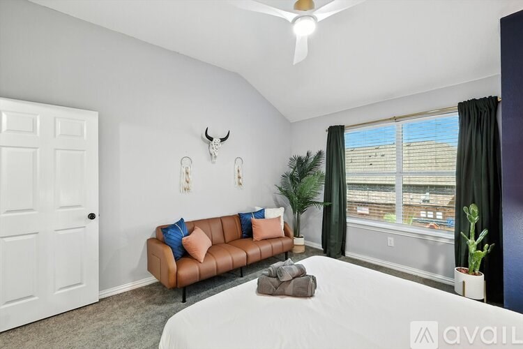 A living room with a brown couch and a white ceiling fan.