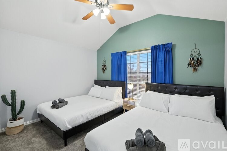 A bedroom with two beds, one with a white comforter and the other with a black headboard.