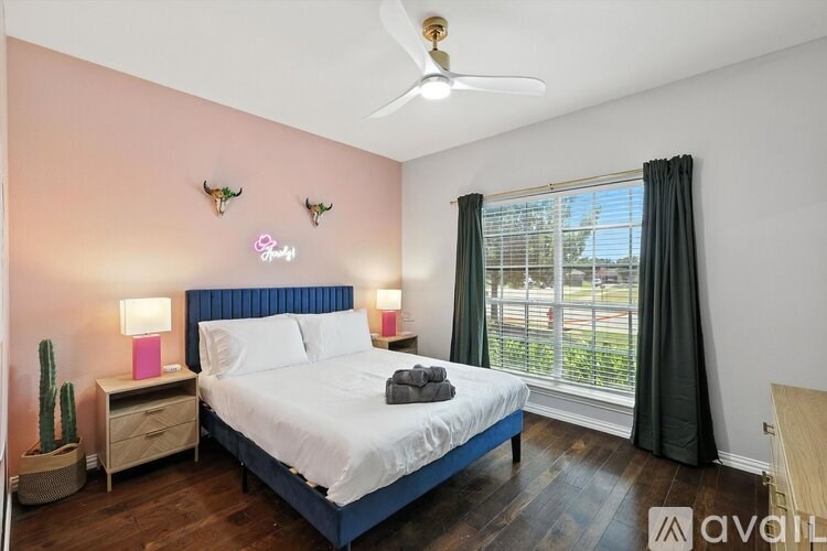 A bedroom with a bed, nightstand, and a window with a view of the outside.