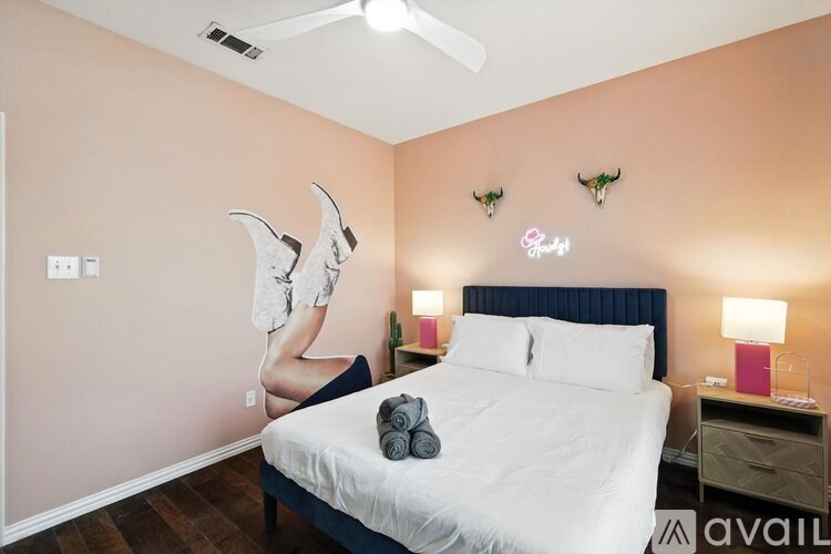 A bedroom with a bed, a ceiling fan, and a wall decoration of a woman in white.