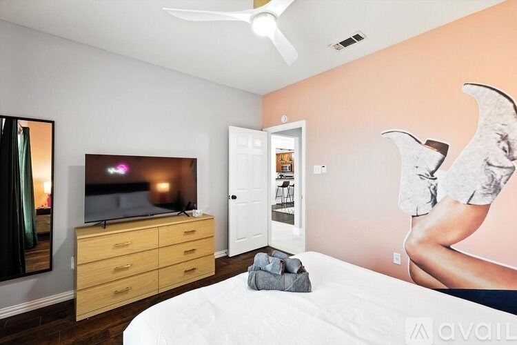 A bedroom with a bed, a dresser, a ceiling fan, and a wall mural.